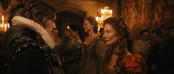 Movie still from “Anonymous” (2011), directed by Roland Emmerich – A group of people standing around each other in a room; Medium shot, Over the shoulder angle