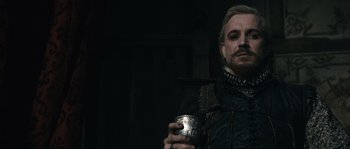 Movie still from “Anonymous” (2011), directed by Roland Emmerich – A man holding a silver cup in a dark room; Close Up shot, Over the shoulder angle