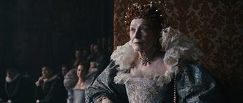 Movie still from “Anonymous” (2011), directed by Roland Emmerich – An older woman wearing a dress and a crown; Close Up shot, Over the shoulder angle