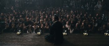 Movie still from “Anonymous” (2011), directed by Roland Emmerich – A woman sitting on the floor in front of a crowd; Wide shot, High angle