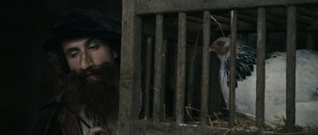 Movie still from “Anonymous” (2011), directed by Roland Emmerich – A man with a long beard looking at a chicken in a cage; Close Up shot, Low angle