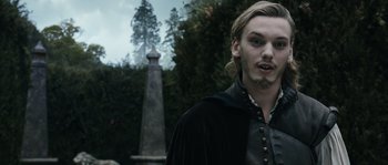Movie still from “Anonymous” (2011), directed by Roland Emmerich – A man in a black and white outfit standing in front of a stone obelisk; Close Up shot, Over the shoulder angle