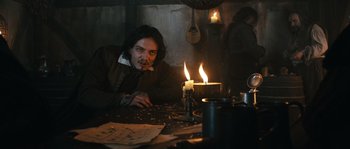 Movie still from “Anonymous” (2011), directed by Roland Emmerich – A man sitting in front of a candle on a table; Medium shot, Over the shoulder angle