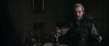 Movie still from “Anonymous” (2011), directed by Roland Emmerich – A man sitting at a table with a glass of wine; Medium shot, Over the shoulder angle