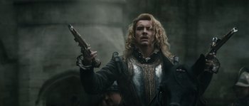 Movie still from “Anonymous” (2011), directed by Roland Emmerich – A man with long blonde hair holding a gun in his hand; Medium shot, Over the shoulder angle