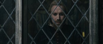Movie still from “Anonymous” (2011), directed by Roland Emmerich – A man with a beard is looking through a fence; Close Up shot, Over the shoulder angle