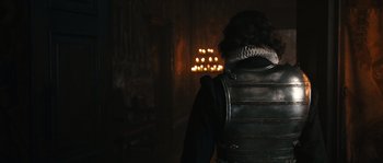 Movie still from “Anonymous” (2011), directed by Roland Emmerich – A man in a leather jacket standing in front of a wall of candles; Medium shot, Over the shoulder angle