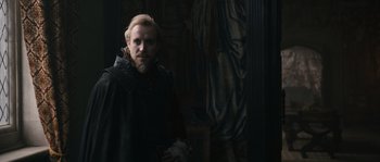 Movie still from “Anonymous” (2011), directed by Roland Emmerich – A man with a beard wearing a black cape; Medium shot, Over the shoulder angle