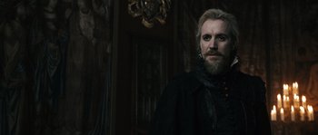 Movie still from “Anonymous” (2011), directed by Roland Emmerich – A man with long hair and a beard standing next to a door; Close Up shot, Over the shoulder angle