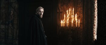 Movie still from “Anonymous” (2011), directed by Roland Emmerich – A man standing in front of a chandelier with lit candles; Medium shot, Low angle