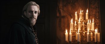 Movie still from “Anonymous” (2011), directed by Roland Emmerich – A man standing in front of candles in a room; Medium shot, Over the shoulder angle