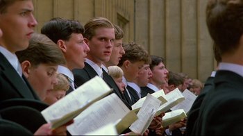 Movie still from “Another Country” (1984), directed by Marek Kanievska – A group of young men standing next to each other holding books; Medium shot, Low angle