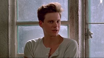 Movie still from “Another Country” (1984), directed by Marek Kanievska – A young man sitting in front of a window looking at the camera; Close Up shot, Low angle