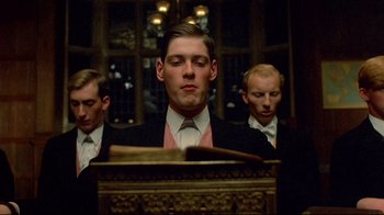 Movie still from “Another Country” (1984), directed by Marek Kanievska – A man in a suit and tie standing in front of a piano; Close Up shot, Low angle