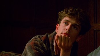 Movie still from “Another Country” (1984), directed by Marek Kanievska – A young man is sitting with his chin resting on his hand; Close Up shot, Low angle