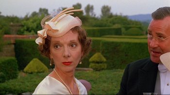 Movie still from “Another Country” (1984), directed by Marek Kanievska – An older woman wearing a hat and a necklace; Close Up shot, Over the shoulder angle
