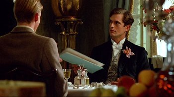 Movie still from “Another Country” (1984), directed by Marek Kanievska – A man sitting at a table with a book in front of him; Medium shot, Over the shoulder angle