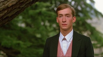 Movie still from “Another Country” (1984), directed by Marek Kanievska – A man in a suit and tie standing in front of a tree; Close Up shot, Low angle