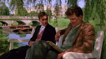 Movie still from “Another Country” (1984), directed by Marek Kanievska – Two men sitting on a bench near a body of water; Medium shot, Low angle