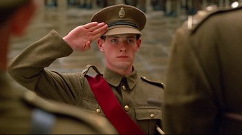 Movie still from “Another Country” (1984), directed by Marek Kanievska – A man in uniform saluting while wearing a red tie; Close Up shot, Low angle