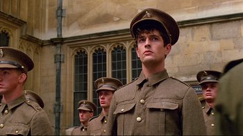 Movie still from “Another Country” (1984), directed by Marek Kanievska – A group of men in military uniforms standing next to each other in front of a building; Medium shot, Low angle