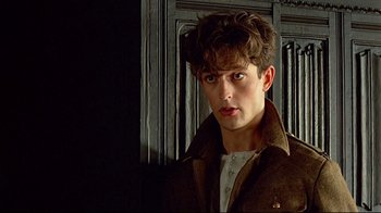 Movie still from “Another Country” (1984), directed by Marek Kanievska – A young man in a brown jacket looking at the camera; Close Up shot, Over the shoulder angle