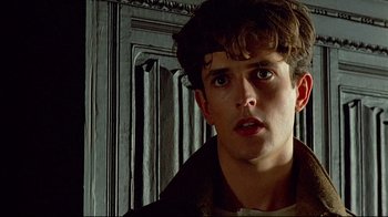 Movie still from “Another Country” (1984), directed by Marek Kanievska – A young man with short brown hair looking at the camera; Close Up shot, Low angle