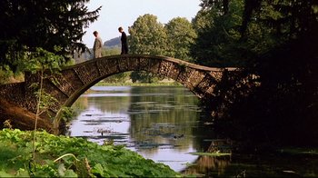 Movie still from “Another Country” (1984), directed by Marek Kanievska – Two people are standing on a bridge over a river; Extreme Wide shot, Over the shoulder angle