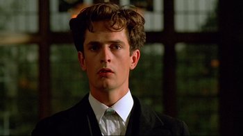 Movie still from “Another Country” (1984), directed by Marek Kanievska – A man in a suit and tie looking at the camera; Close Up shot, Low angle