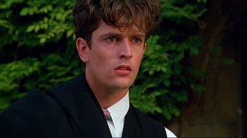Movie still from “Another Country” (1984), directed by Marek Kanievska – A man with a beard and a white shirt and a black vest; Close Up shot, Over the shoulder angle