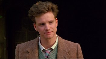 Movie still from “Another Country” (1984), directed by Marek Kanievska – A young man with brown hair and wearing a suit and tie; Close Up shot, Over the shoulder angle