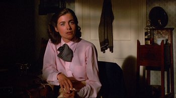 Movie still from “Another Country” (1984), directed by Marek Kanievska – A woman sitting in a chair wearing a tie; Close Up shot, Over the shoulder angle