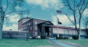 Movie still from “Another Earth” (2011), directed by Mike Cahill – A large building with a flag flying outside of it; Extreme Wide shot, Low angle