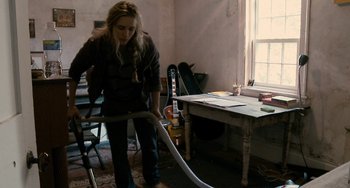 Movie still from “Another Earth” (2011), directed by Mike Cahill – A woman is vacuuming the floor in a room; Medium shot, High angle