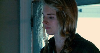 Movie still from “Another Earth” (2011), directed by Mike Cahill – A woman with long blonde hair is looking down; Close Up shot, Over the shoulder angle