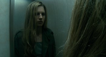 Movie still from “Another Earth” (2011), directed by Mike Cahill – A woman looking in the mirror in front of a wall; Close Up shot, Over the shoulder angle
