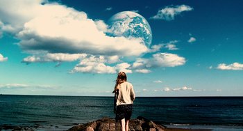 Movie still from “Another Earth” (2011), directed by Mike Cahill – A woman standing on a pier looking out at the ocean; Extreme Wide shot, Low angle