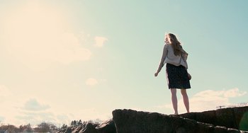 Movie still from “Another Earth” (2011), directed by Mike Cahill – A woman standing on top of a rock looking out at the sky; Wide shot, Low angle