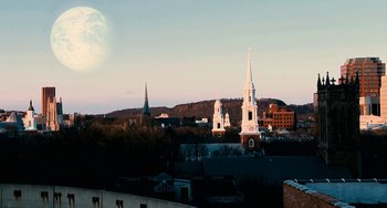 Movie still from “Another Earth” (2011), directed by Mike Cahill – A view of a city skyline at dusk with a moon in the background; Extreme Wide shot, Low angle
