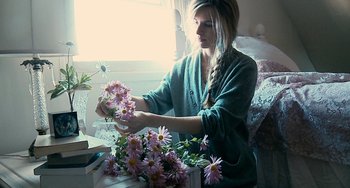 A woman sitting in front of a table with flowers in it