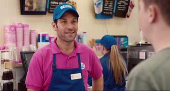 Movie still from “Ant-Man” (2015), directed by Peyton Reed – A man in a pink shirt and blue hat is standing in front of a counter; Medium shot, Over the shoulder angle