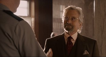 Movie still from “Ant-Man” (2015), directed by Peyton Reed – An older man wearing a suit and tie looking into a mirror; Close Up shot, Over the shoulder angle