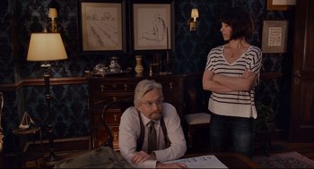Movie still from “Ant-Man” (2015), directed by Peyton Reed – An older man sitting at a desk with a woman standing next to him; Medium shot, Over the shoulder angle