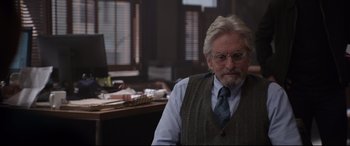 Movie still from “Ant-Man and the Wasp” (2018), directed by Peyton Reed – An older man sitting at a computer desk in front of a computer; Medium shot, Over the shoulder angle