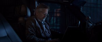Movie still from “Ant-Man and the Wasp” (2018), directed by Peyton Reed – An older man sitting in the back of a car looking at a laptop computer; Medium shot, Over the shoulder angle