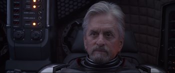 Movie still from “Ant-Man and the Wasp” (2018), directed by Peyton Reed – An older man with a gray beard wearing a suit; Close Up shot, Over the shoulder angle