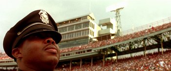 Movie still from “Any Given Sunday” (1999), directed by Oliver Stone – A man in a baseball uniform is in a stadium; Close Up shot, Low angle