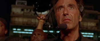 Movie still from “Any Given Sunday” (1999), directed by Oliver Stone – A man with a microphone in his ear and another man with a microphone in his ear; Close Up shot, Low angle