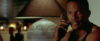 Movie still from “Any Given Sunday” (1999), directed by Oliver Stone – A man holding a cell phone up to his ear; Close Up shot, Low angle
