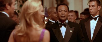 Movie still from “Any Given Sunday” (1999), directed by Oliver Stone – A man in a tuxedo standing next to a woman in a black dress; Close Up shot, Low angle